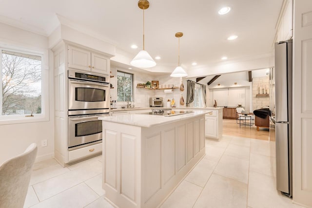 kitchen with a center island, crown molding, appliances with stainless steel finishes, white cabinets, and light tile patterned flooring