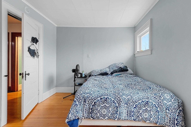 bedroom with light wood-style floors, baseboards, and ornamental molding