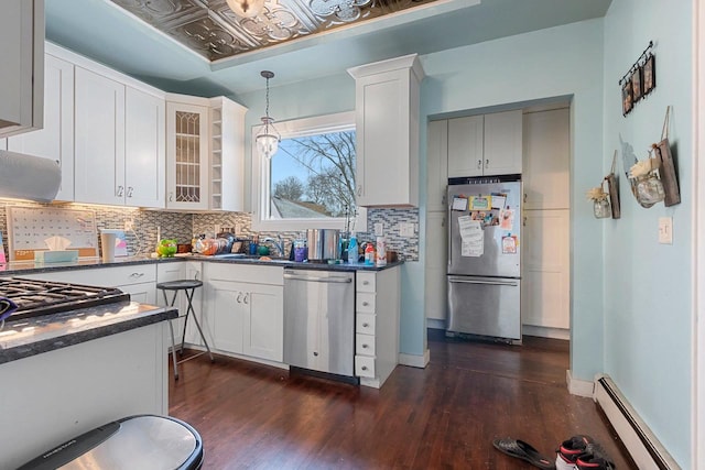 kitchen with a baseboard heating unit, stainless steel appliances, dark wood-type flooring, tasteful backsplash, and dark countertops