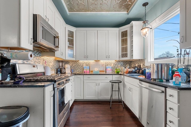 kitchen with appliances with stainless steel finishes, dark countertops, dark wood-type flooring, and backsplash