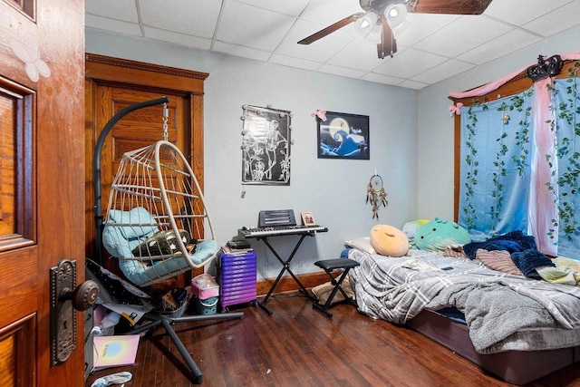 bedroom featuring a ceiling fan, a drop ceiling, and wood finished floors