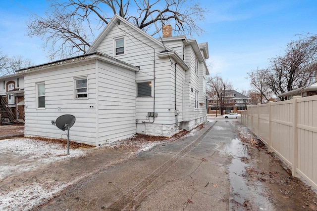 view of side of property featuring fence and a chimney