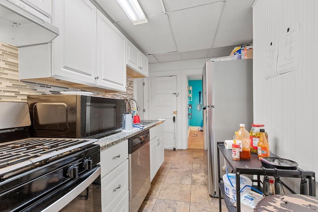 kitchen featuring a drop ceiling, under cabinet range hood, white cabinets, black appliances, and tasteful backsplash