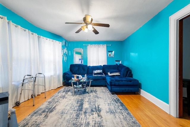 living area with ceiling fan, baseboards, and wood finished floors