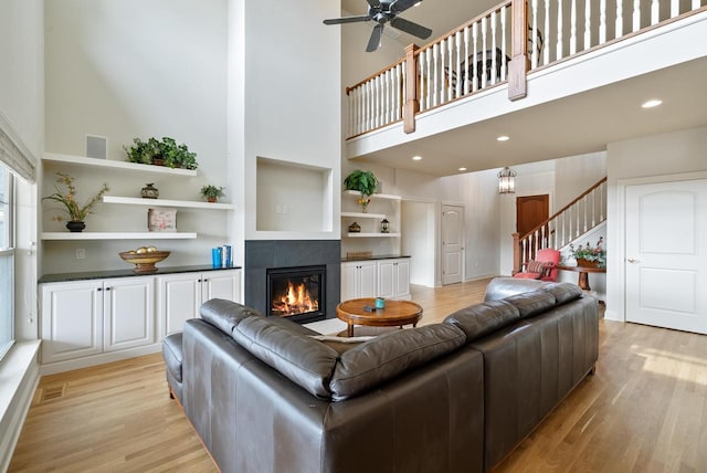 living room featuring stairs, light wood-type flooring, visible vents, and a tile fireplace