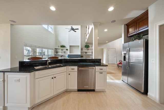 kitchen featuring a ceiling fan, appliances with stainless steel finishes, dark stone countertops, a sink, and recessed lighting