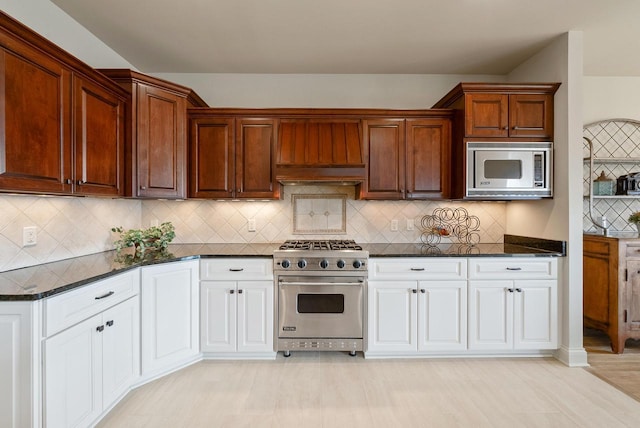 kitchen featuring appliances with stainless steel finishes, backsplash, white cabinetry, and wall chimney range hood