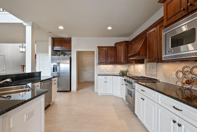 kitchen featuring decorative backsplash, dark stone countertops, stainless steel appliances, a sink, and recessed lighting