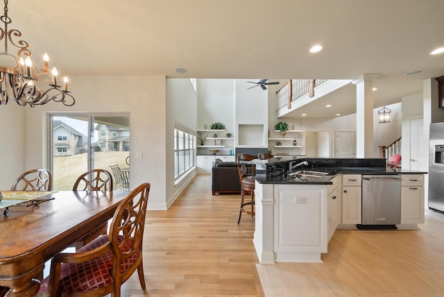 kitchen with dark countertops, open floor plan, stainless steel appliances, light wood-type flooring, and a sink