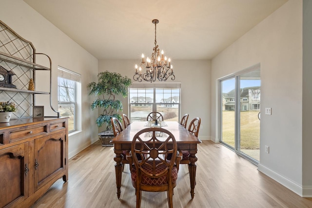 dining room featuring a notable chandelier, light wood-type flooring, a wealth of natural light, and baseboards