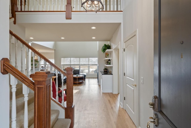 foyer with light wood-style floors, recessed lighting, a high ceiling, and stairs