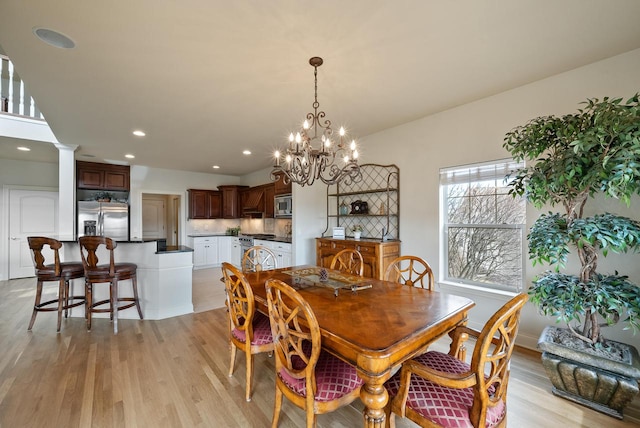 dining room with light wood-style floors, recessed lighting, and ornate columns