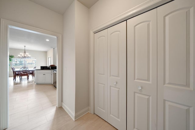 hall with baseboards and a notable chandelier