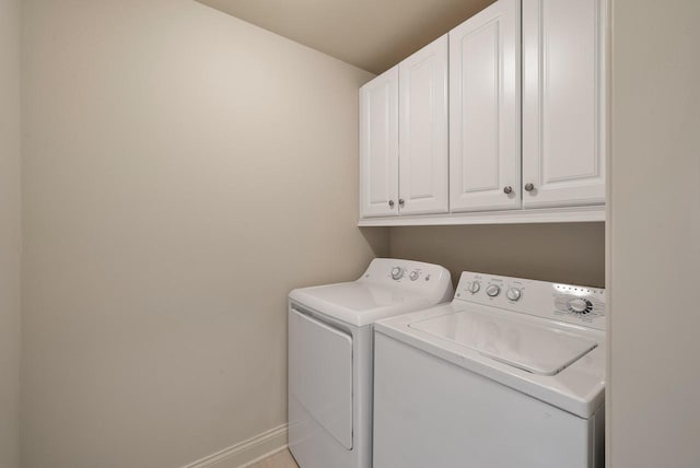 clothes washing area with washing machine and dryer, cabinet space, and baseboards