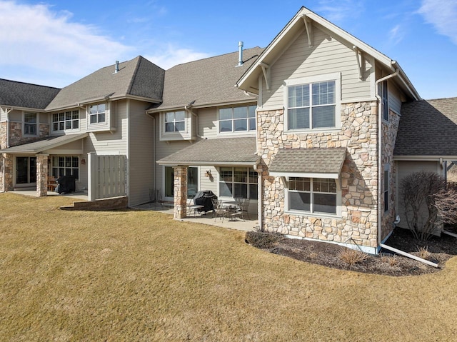 back of house featuring stone siding, a yard, a patio, and a shingled roof