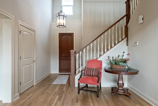 foyer entrance featuring a towering ceiling, stairway, baseboards, and wood finished floors