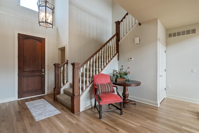 foyer with baseboards, stairs, visible vents, and wood finished floors