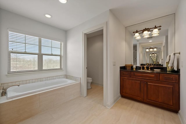 bathroom featuring baseboards, a garden tub, vanity, and toilet