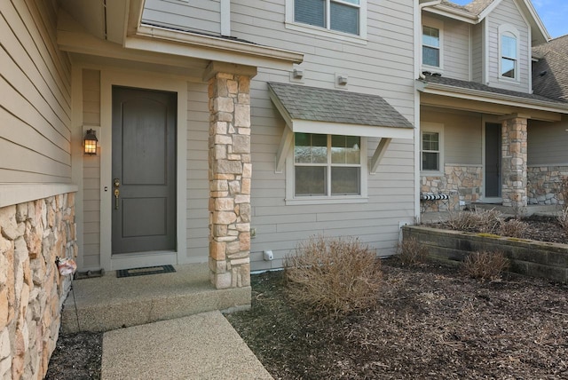 property entrance with stone siding and a shingled roof