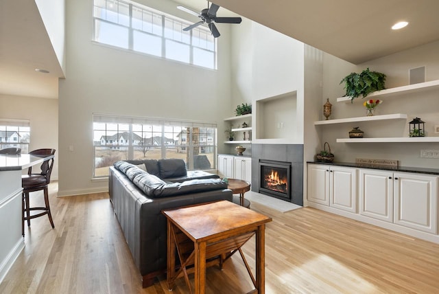 living room with light wood-type flooring, a healthy amount of sunlight, and a tiled fireplace