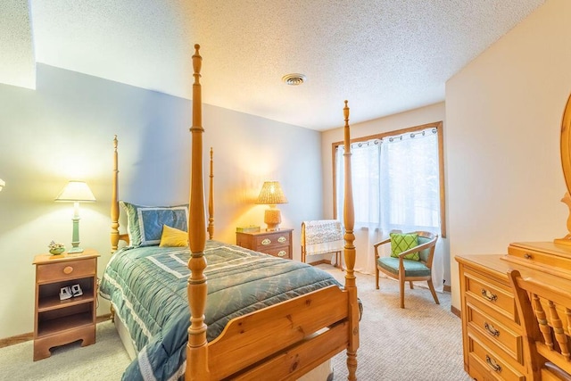 bedroom featuring light carpet, visible vents, and a textured ceiling