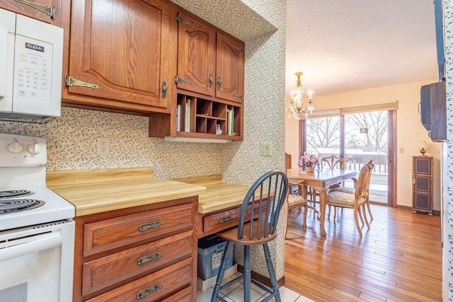 kitchen featuring white appliances, built in study area, brown cabinets, light countertops, and light wood-type flooring