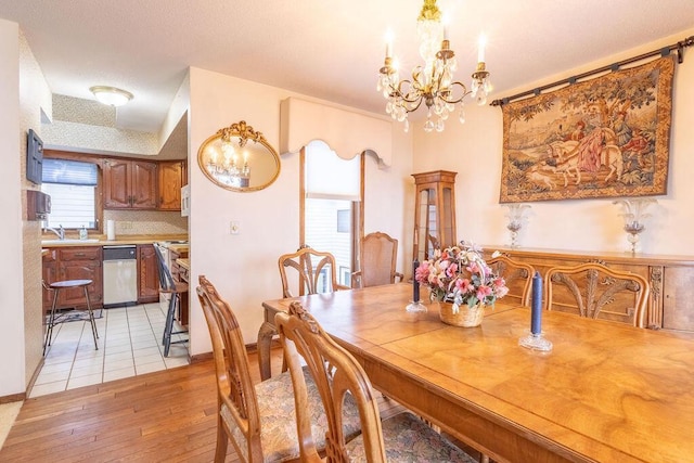 dining area with baseboards, light wood finished floors, and an inviting chandelier