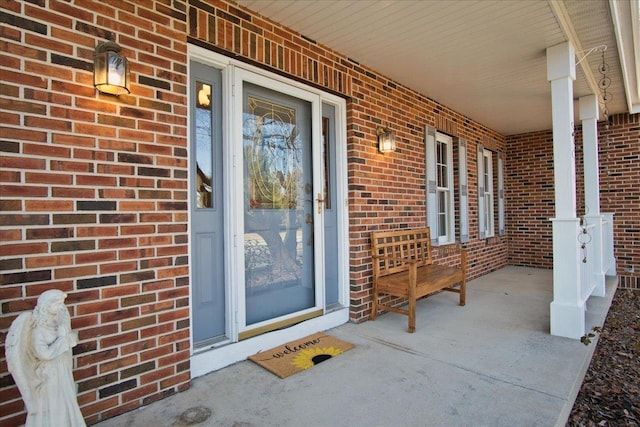 doorway to property featuring brick siding and covered porch