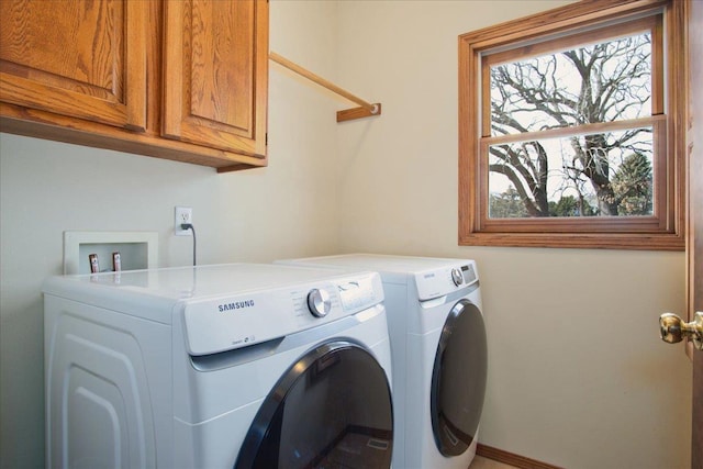 washroom with washer and dryer, baseboards, cabinet space, and a wealth of natural light