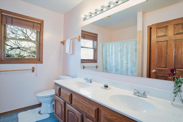 bathroom featuring double vanity, toilet, tile patterned floors, and a sink