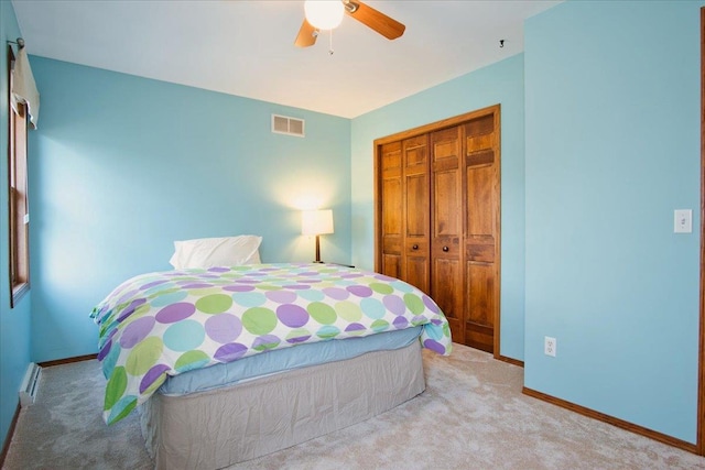 carpeted bedroom with a ceiling fan, baseboards, visible vents, and a closet