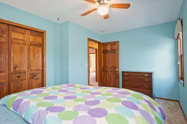 bedroom with a ceiling fan, baseboards, a closet, and light carpet