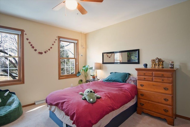 bedroom featuring baseboard heating, light colored carpet, baseboards, and multiple windows