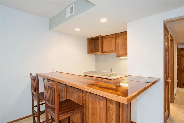 bar featuring visible vents, baseboards, recessed lighting, bar, and a sink