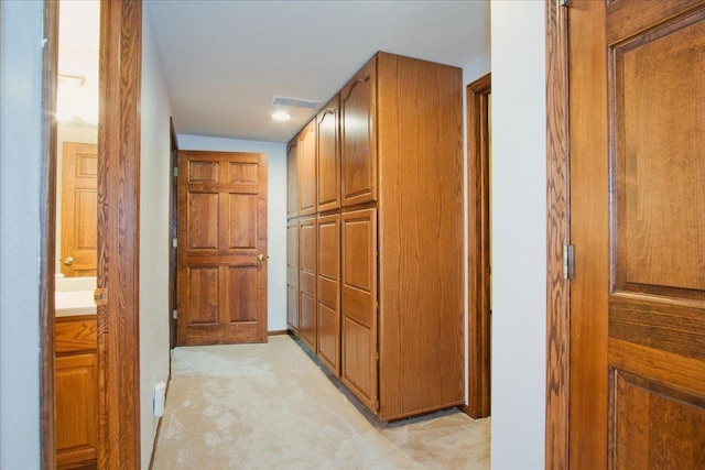 corridor featuring visible vents, baseboards, and light colored carpet