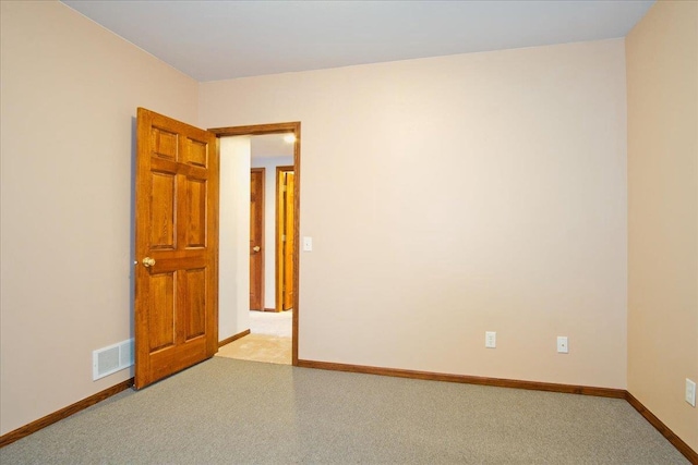 unfurnished room with light carpet, visible vents, and baseboards