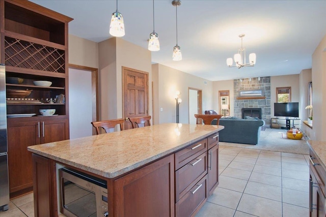 kitchen featuring light stone counters, stainless steel microwave, a kitchen island, a chandelier, and hanging light fixtures