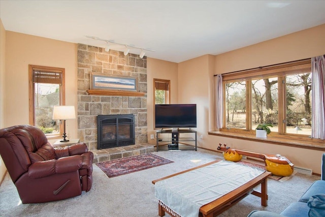 carpeted living area with a wealth of natural light, a fireplace, a baseboard heating unit, and baseboards