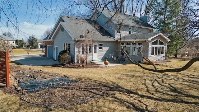 back of property with a garage, concrete driveway, and a yard