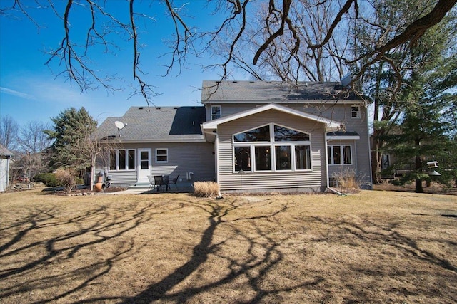 rear view of property featuring a patio, a yard, and a shingled roof