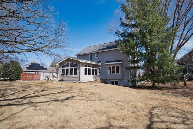 rear view of house featuring fence and a lawn