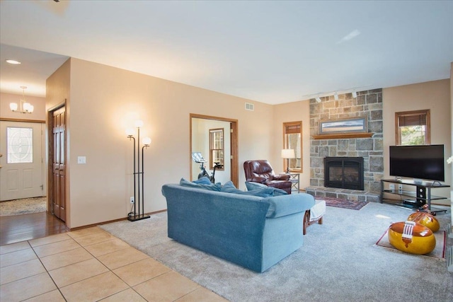 living area with tile patterned floors, visible vents, an inviting chandelier, a fireplace, and baseboards