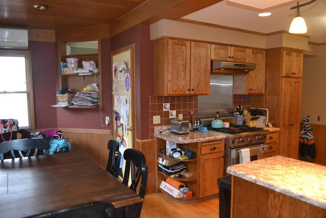 kitchen featuring under cabinet range hood, a wall mounted AC, high end range, open shelves, and brown cabinetry