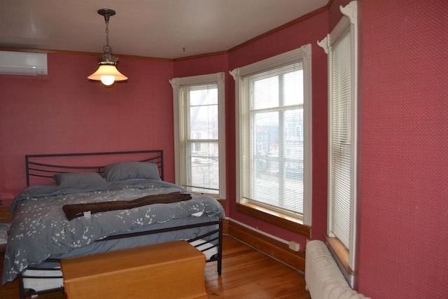 bedroom with radiator, crown molding, wood finished floors, and a wall mounted air conditioner