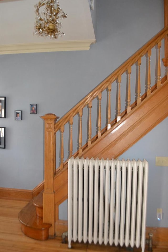 stairway featuring an inviting chandelier and radiator heating unit