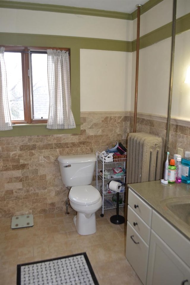 bathroom with a wainscoted wall, radiator heating unit, toilet, and tile walls