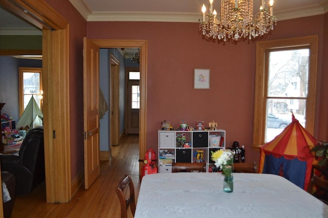 dining space featuring ornamental molding, a chandelier, and wood finished floors