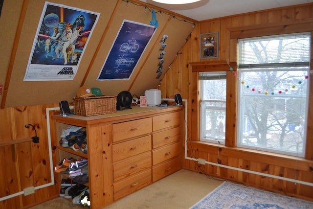 bedroom featuring light colored carpet, vaulted ceiling, and wooden walls