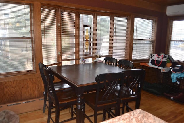 dining area with a wall mounted AC and light wood-style flooring