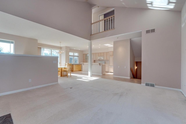 unfurnished living room with visible vents, light colored carpet, a high ceiling, and baseboards